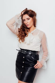 Portrait of a beautiful woman with hair curls in a white blouse and black skirt