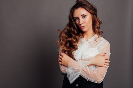 Portrait of a beautiful woman with hair curls in a white blouse and black skirt