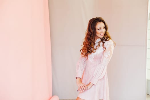 Portrait of a beautiful woman with hair curls in a pink dress