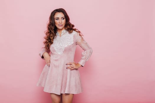 Portrait of a beautiful woman with hair curls in a pink dress