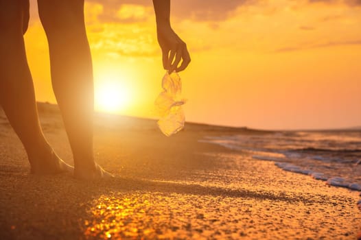 Volunteer woman collecting plastic holey bottle for beach cleanup, women cleaning up trash, ecology concept and World Environment Day, saving the Earth concept.