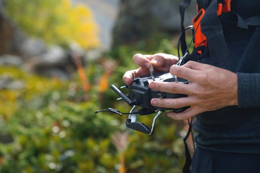 Close-up of a man's hands holding a remote control to control an FPV racing drone. flying an unmanned aircraft.