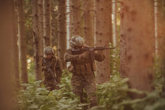 A group of modern warfare soldiers is fighting a war in dangerous remote forest areas. A group of soldiers is fighting on the enemy line with modern weapons. The concept of warfare and military conflicts.