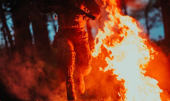 Soldier in Action at Night in the Forest Area. Night Time Military Mission jumping over fire.