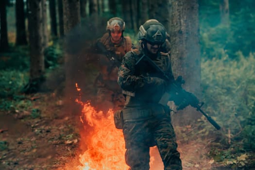 Soldier in Action at Night in the Forest Area. Night Time Military Mission jumping over fire.