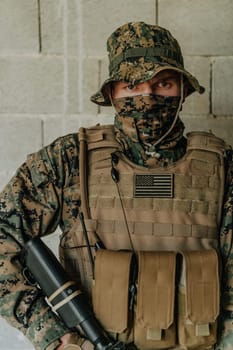 A soldier in uniform stands in front of a stone wall in full war gear preparing for battle.