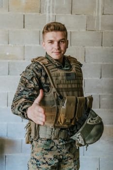 A soldier in uniform stands in front of a stone wall with an outstretched hand. The concept of military and war partnership.