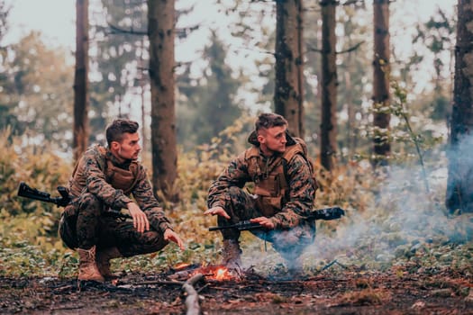 Two exhausted soldiers sitting by the fire after a weary and heavy war battle.