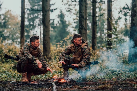 Two exhausted soldiers sitting by the fire after a weary and heavy war battle.