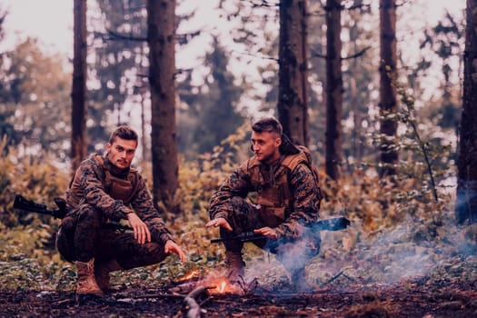 Two exhausted soldiers sitting by the fire after a weary and heavy war battle.