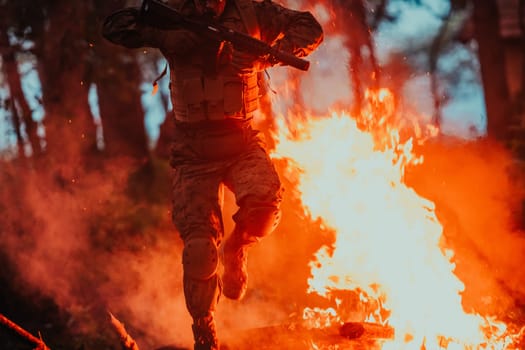 Soldier in Action at Night in the Forest Area. Night Time Military Mission jumping over fire.