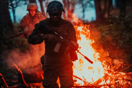 Soldier in Action at Night in the Forest Area. Night Time Military Mission jumping over fire.