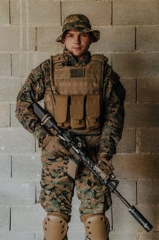 A soldier in uniform stands in front of a stone wall in full war gear preparing for battle.