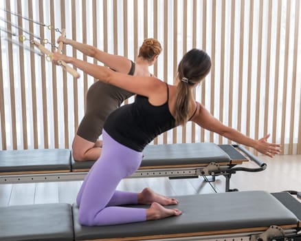 Two pregnant women do Pilates exercises on a reformer