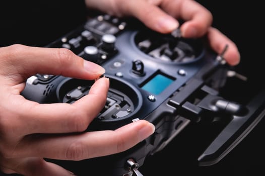 female hands holding sticks on the remote control of a drone, close-up, indoors.