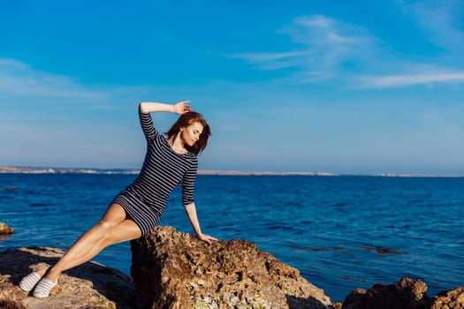 girl sits on the rocky beach enjoys sunshine 1