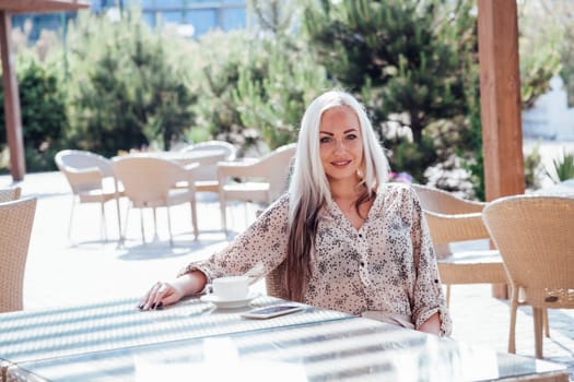 blonde girl sitting at the beach restaurant coffee drinkers