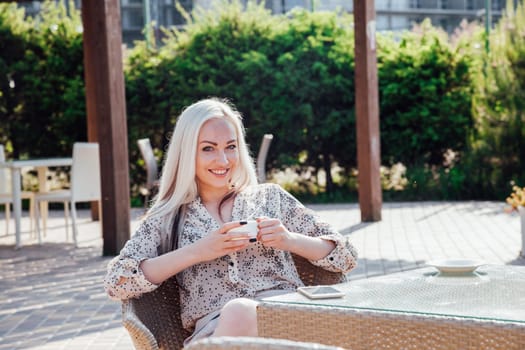 blonde girl sitting at the beach restaurant coffee drinkers