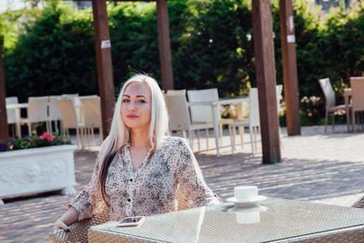 blonde girl sitting at the beach restaurant coffee drinkers