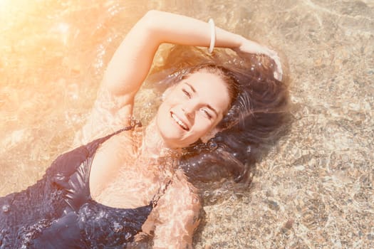 Woman travel sea. Young Happy woman in a long red dress posing on a beach near the sea on background of volcanic rocks, like in Iceland, sharing travel adventure journey