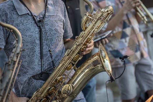 Close-up of a musician's hands playing the trumpet during a vibrant live performance in daylight.