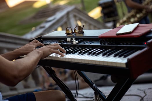 Close-up of a pianist's hands skillfully playing the keyboard during a live daylight performance.