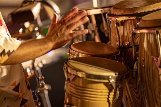 The hands of a tribal drummer, captured during an atmospheric night concert with fog.