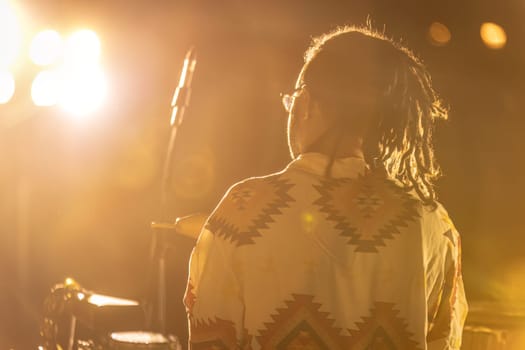 A tribal drummer immersed in performance, surrounded by fog at a night concert.