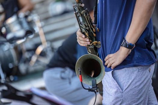 Close-up of a musician's hands playing the trumpet during a vibrant live performance in daylight.