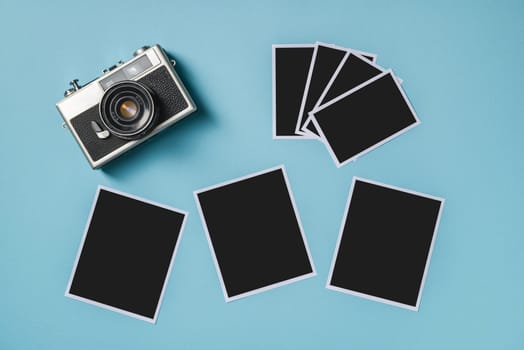 Vintage photo camera and empty photo frames on blue background. Travel moment concept