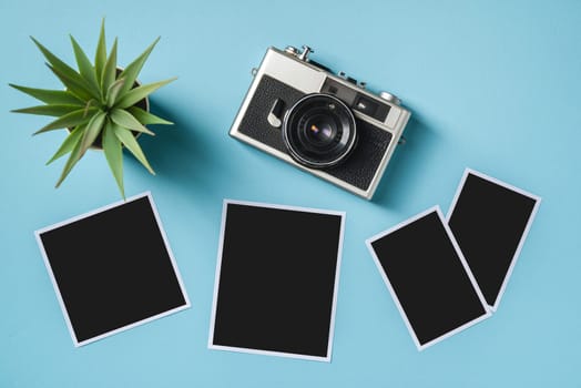 Vintage photo camera and empty photo frames on blue background. Travel moment concept