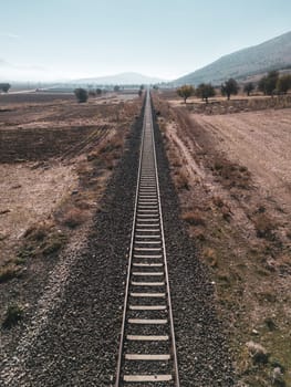 Top view of the train track passing through the arid land, taken with a drone