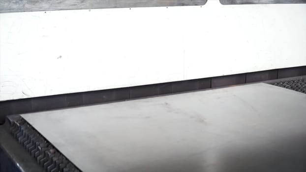 Sandwich panel or metal work profiling factory. Clip. Continuous sheet of metallic material being fed through machine. New modern machine tool conveyor for roll forming, blue toned with sunlight effect.