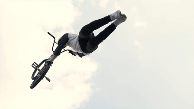 Russia - Moscow, 08.15.2019: two racers at competition jumping from a springboard on blue cloudy sky background. Two BMX riders making tricks.