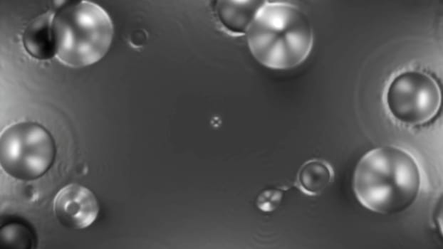 Boiling unknown liquid substance. Design. Round spherical bubbles appear on calm surface