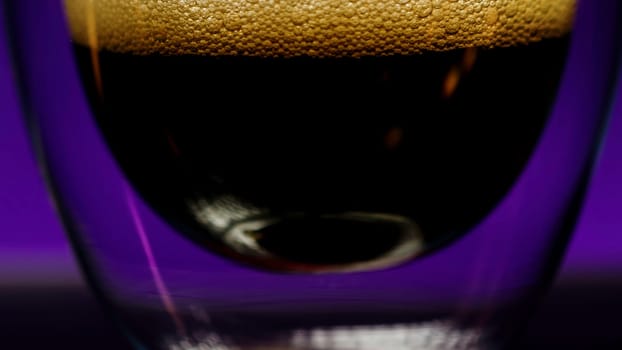 Soda bubbles in a glass against a dark wall changing colors. Stock clip. Soft drink in transparent glass with double bottom