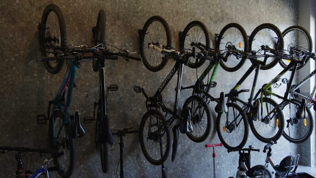 Many bicycles hanged on a white wall. Stock footage. Bike and children scooters parking inside the building entrance