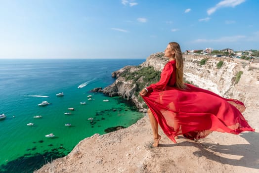 Red Dress Woman sea Cliff. A beautiful woman in a red dress and white swimsuit poses on a cliff overlooking the sea on a sunny day. Boats and yachts dot the background