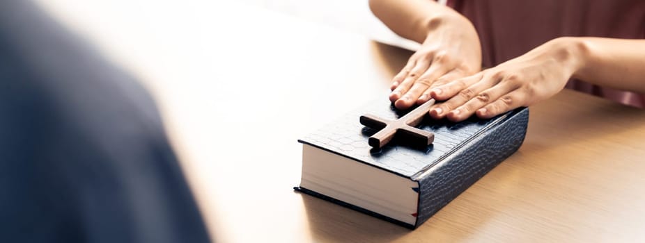 Close-up women prayer deliver holy bible book and holy cross to male believer. Spreading religion symbol. Concept of hope, religion, christianity and god blessing. Warm background. Burgeoning.