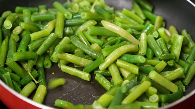 Green beans are being cooked in a pan, close up. Selective focus