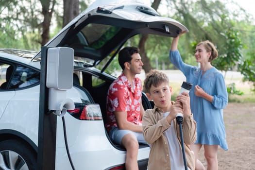 Family road trip vacation with electric vehicle, lovely family recharge EV car with green and clean energy. Natural and eco friendly car travel for sustainable environment. Perpetual