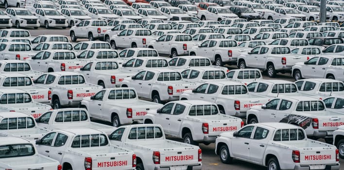 Lamchabang, Thailand - July 02, 2023 A cloudy day at the car factory reveals rows of new vehicles in the distribution center. Top view captures the crowded parking, symbolizing modern manufacturing.