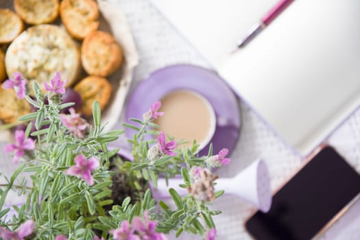 Lavender french breakfast, goat cheese and oven baked baguette, notepad, smartphone, flat lay food, female hand dipping slice of bread in cheese,depth of field, photo in blur quality photo