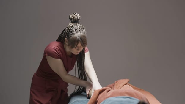 Woman does massage on isolated background. Action. Woman professionally massages client. Massage in professional spa salon.