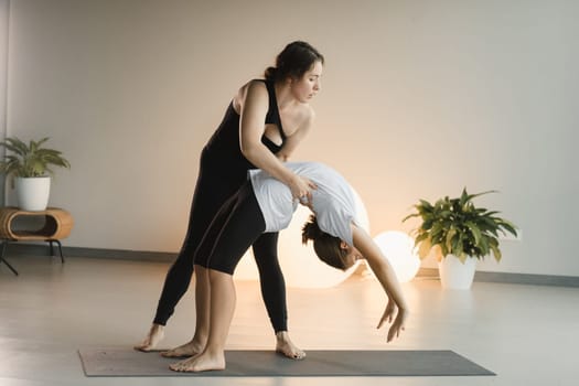 Mom and teenage daughter do gymnastics together in the fitness room. A woman and a girl train in the gym.