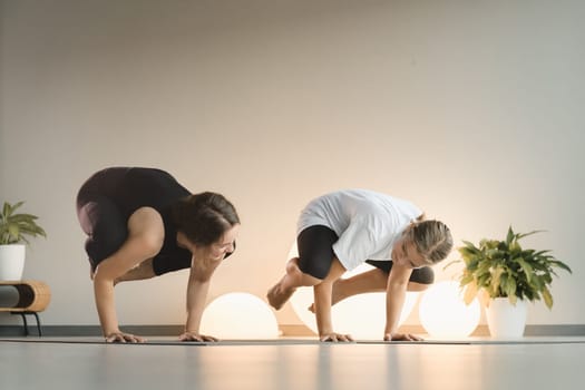 Mom and teenage daughter do gymnastics together in the fitness room. A woman and a girl train in the gym.