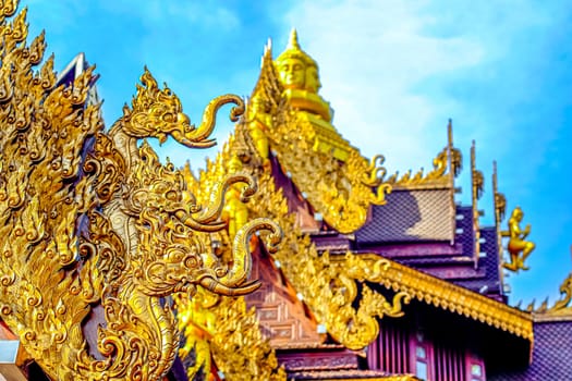 Traditional Thai Style Animal Gods Carved on Roof Decorations Against a Blue Sky