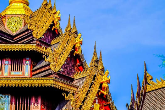 Traditional Thai Style Animal Gods Carved on Roof Decorations Against a Blue Sky