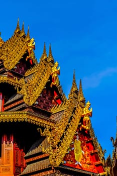 Traditional Thai Style Animal Gods Carved on Roof Decorations Against a Blue Sky