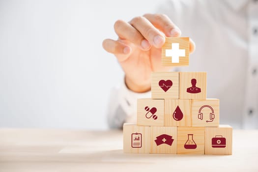 Wooden block held by hand showcases healthcare and medical icons. Conveys safety, health, and family well-being, embodying pharmacy, heart care, and happiness. health care concept